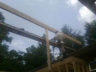 Carpenter setting a ridge beam over a new addition frame — Ice Dam Removal by Roofing Brothers in Newfield